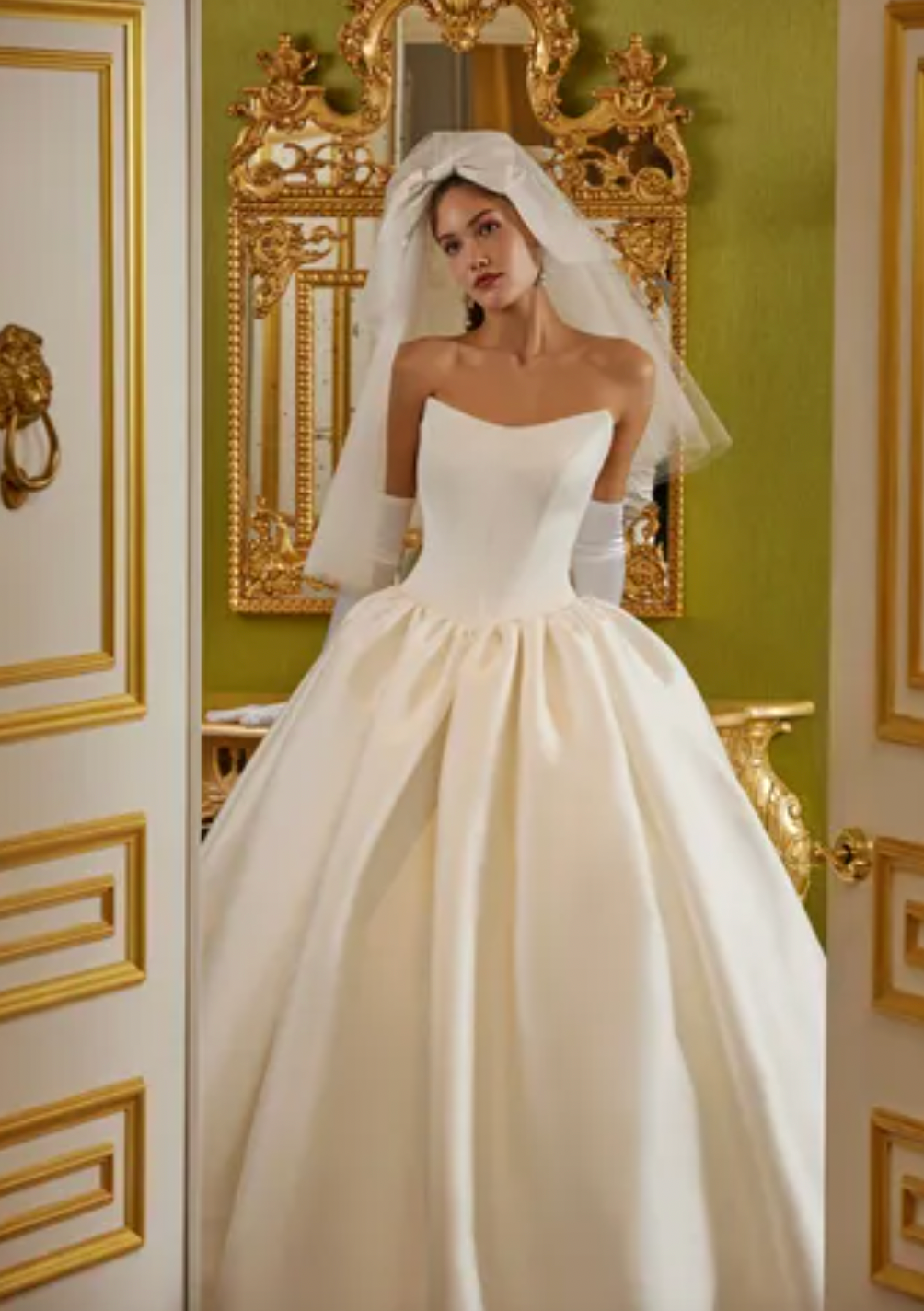 Luxurious and elegant, the Demia Gown is crafted from Italian Stretch Mikado fabric and features a cat eye neckline and basque waist for a flattering silhouette. The pleated and gathered ballgown is adorned with signature bow accents on the back bodice, making it a perfect pick for a special occasion.