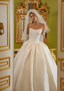 Luxurious and elegant, the Demia Gown is crafted from Italian Stretch Mikado fabric and features a cat eye neckline and basque waist for a flattering silhouette. The pleated and gathered ballgown is adorned with signature bow accents on the back bodice, making it a perfect pick for a special occasion.