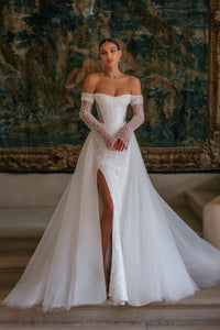 Effie is a luxurious fitted mermaid gown made of exclusive beaded lace. The off-shoulder neckline bares the collarbones adding seductiveness, the corset is decorated with sheer nude side pannels and long translucent lace sleeves look extravagant. The sheath skirt is embellished with thigh high slit and a Tulle overskirt is fastened on the waistline.