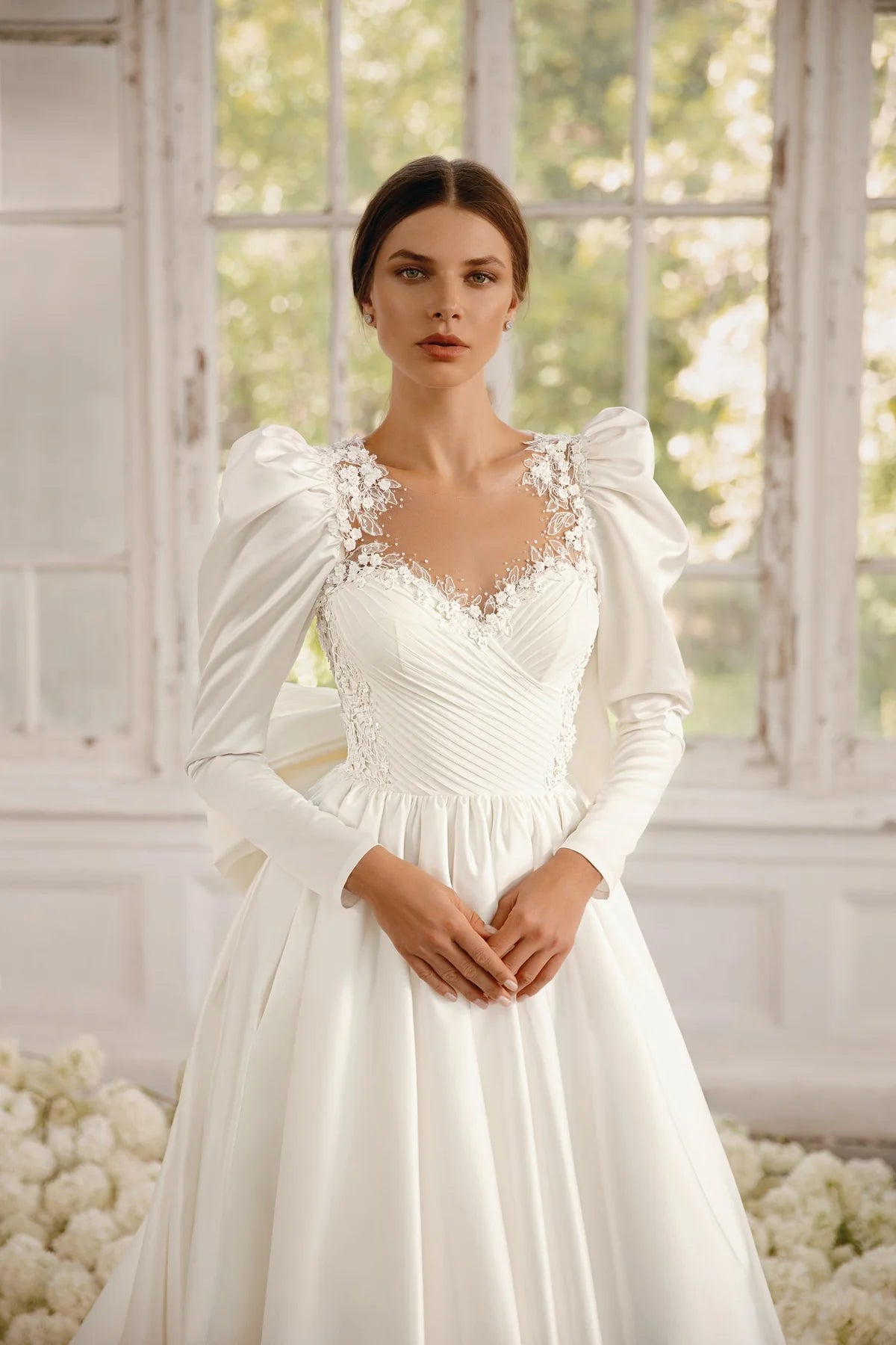 The Rosalee Gown is a breathtaking A-line wedding dress made of luxurious silk satin. The stunning corset features a unique draped design and voluminous puffed sleeves, while delicate hand-embroidered lace adorns the neckline and waistline. With hidden pockets and a removable sash, this dress effortlessly combines elegance and practicality.