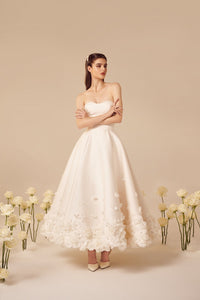 The Rosette Dress is the perfect blend of bold and romantic. Channel your inner Carrie Bradshaw and make a statement at any wedding event. Designed by the same designer as Taylor Swift's iconic Enchanted tour dress, this dress features beautiful rosette details throughout. Embrace this timeless trend with this midi silk wedding dress.