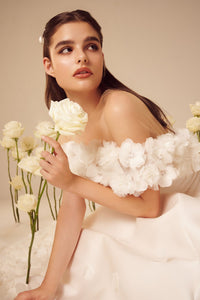 The Rosette Dress is the perfect blend of bold and romantic. Channel your inner Carrie Bradshaw and make a statement at any wedding event. Designed by the same designer as Taylor Swift's iconic Enchanted tour dress, this dress features beautiful rosette details throughout. Embrace this timeless trend with this midi silk wedding dress.