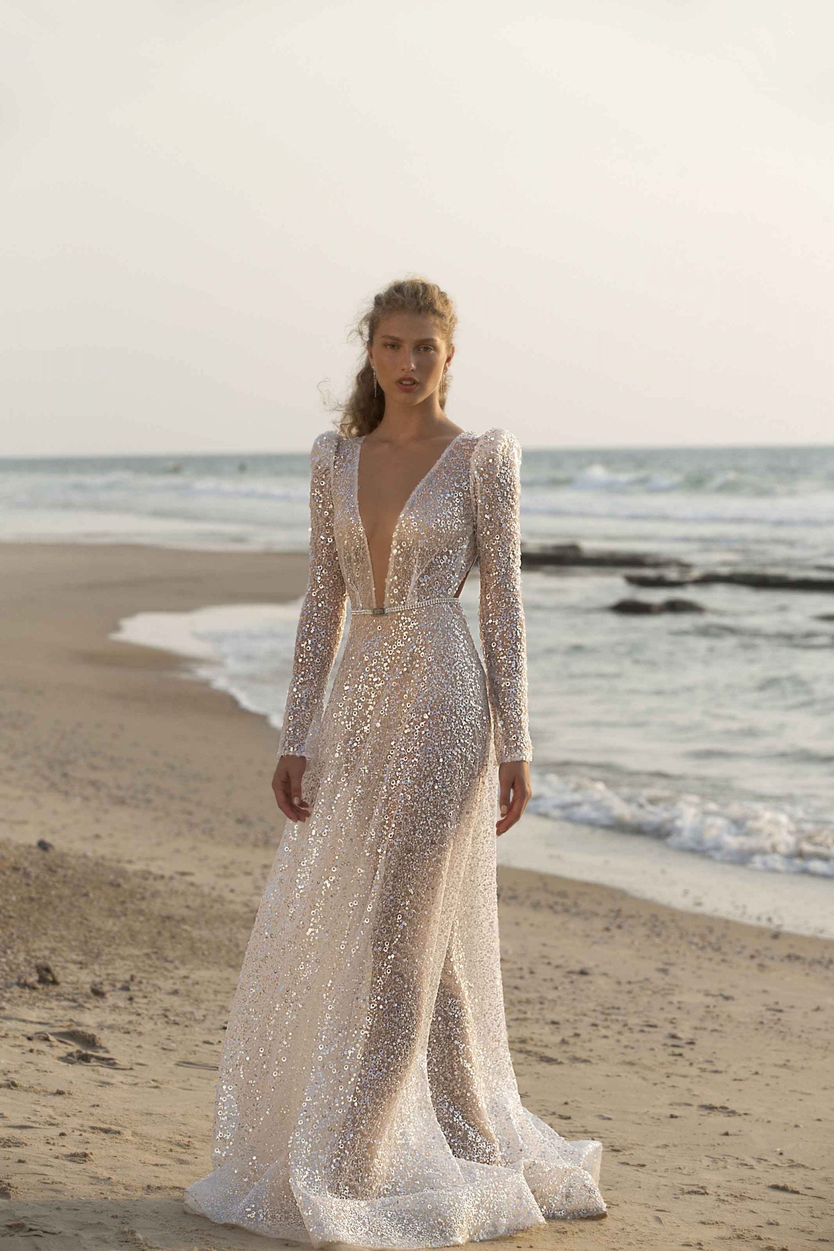 Unleash your inner goddess with the Denisse Gown. This luxurious bridal gown features stunning crystal accents, soft and flowing long sleeves, and a striking mermaid silhouette. Make a grand and graceful entrance on your special day with this elegant and beautiful robe.