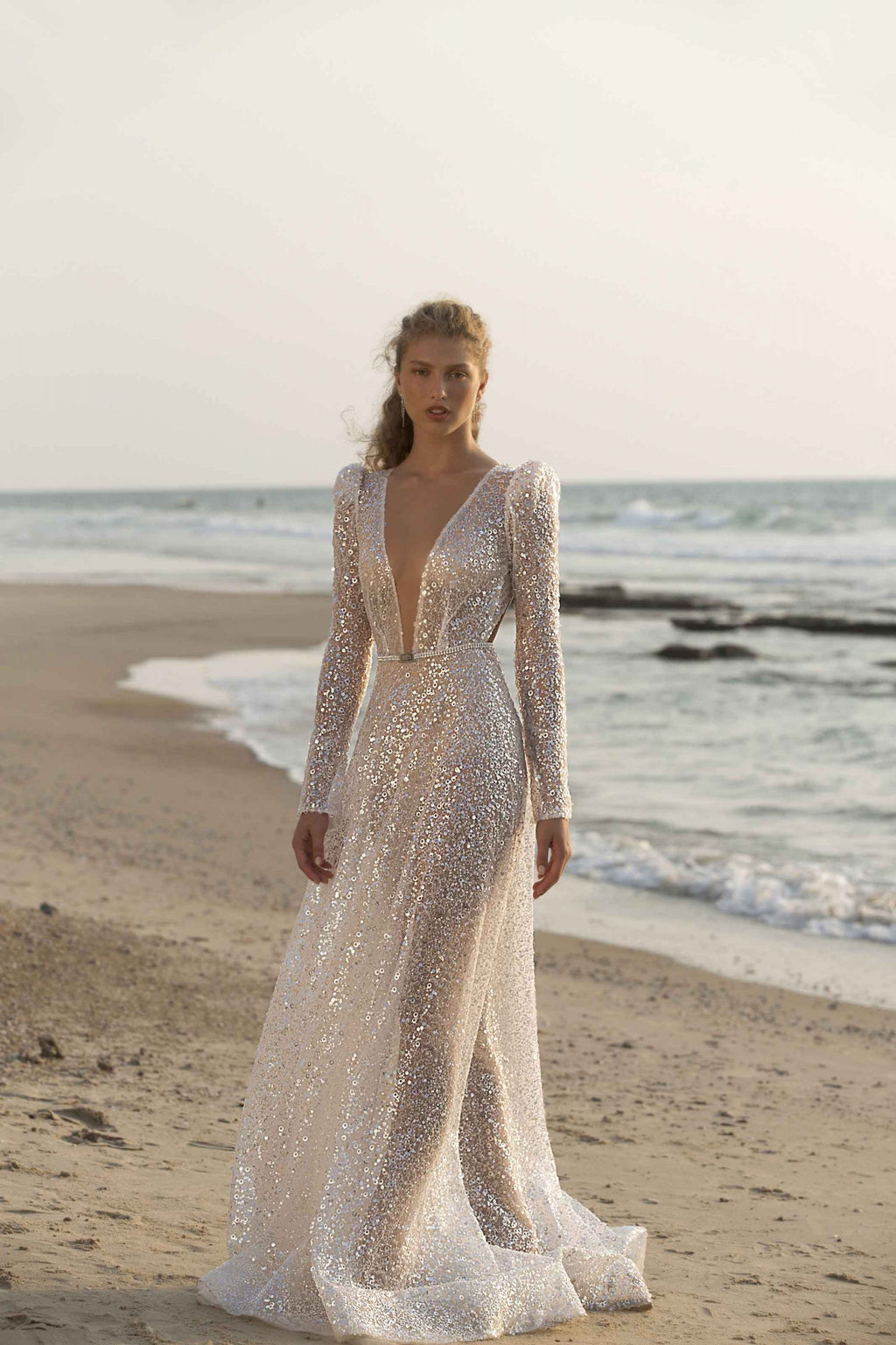 Unleash your inner goddess with the Denisse Gown. This luxurious bridal gown features stunning crystal accents, soft and flowing long sleeves, and a striking mermaid silhouette. Make a grand and graceful entrance on your special day with this elegant and beautiful robe.