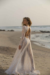Unleash your inner goddess with the Denisse Gown. This luxurious bridal gown features stunning crystal accents, soft and flowing long sleeves, and a striking mermaid silhouette. Make a grand and graceful entrance on your special day with this elegant and beautiful robe.