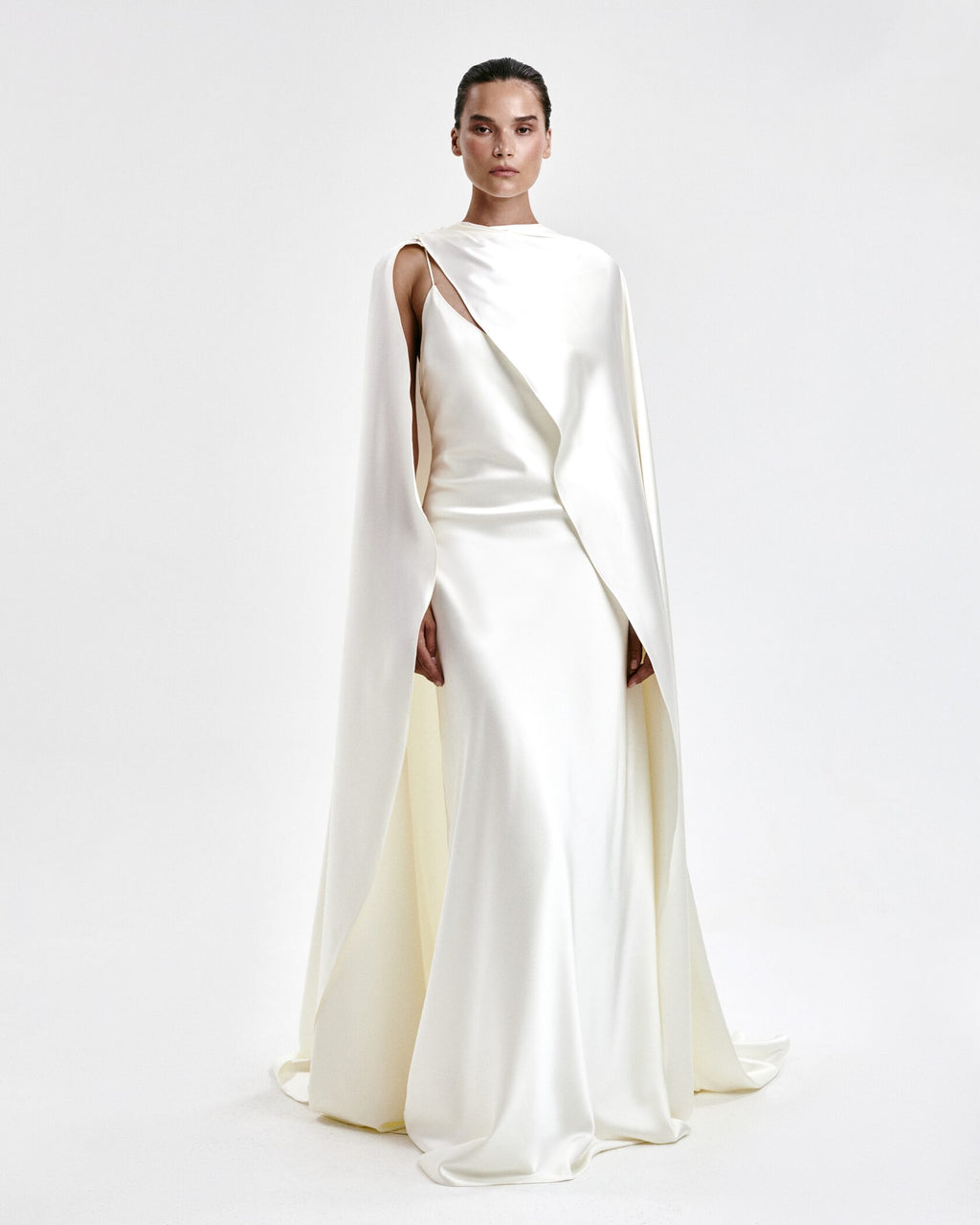 A laconic cape with a smooth texture — a luxurious attribute of the image that emphasizes the elegance and inner strength of its owner. The soft overflow of the fabric, the exquisite silhouette and train make the product expressive and self-sufficient. The composition was chosen consciously: the material does not wrinkle, retains its shape and provides an impeccable appearance throughout the evening. Becomes the final chord in a special event without requiring additional details. 