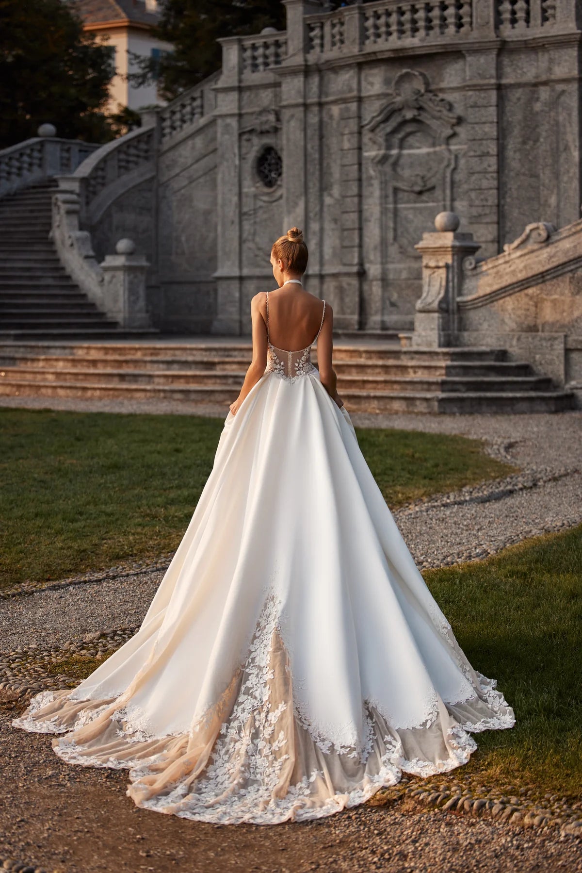 Elevate your special day with the Nelly Gown. This ballgown-style dress features a cinched waist and a dramatic train, while delicate tulle straps, lace flowers, and intricate beading add a touch of romance. The open back and subtle beaded belt add a modern twist to this traditional design. The full satin skirt is adorned with stunning lace details for a look that exudes elegance and grace.