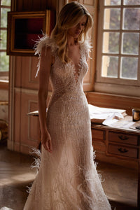 Get ready to turn heads in this one-of-a-kind Dress Feline! Featuring a sheer nude fabric with a delicate train, a V-neck corset, and intricate embroidered lace adorned with beads and glitter. The unique touches of feathers, crystals, and hand-made flowers on the shoulders will make you feel like a glamorous feline.