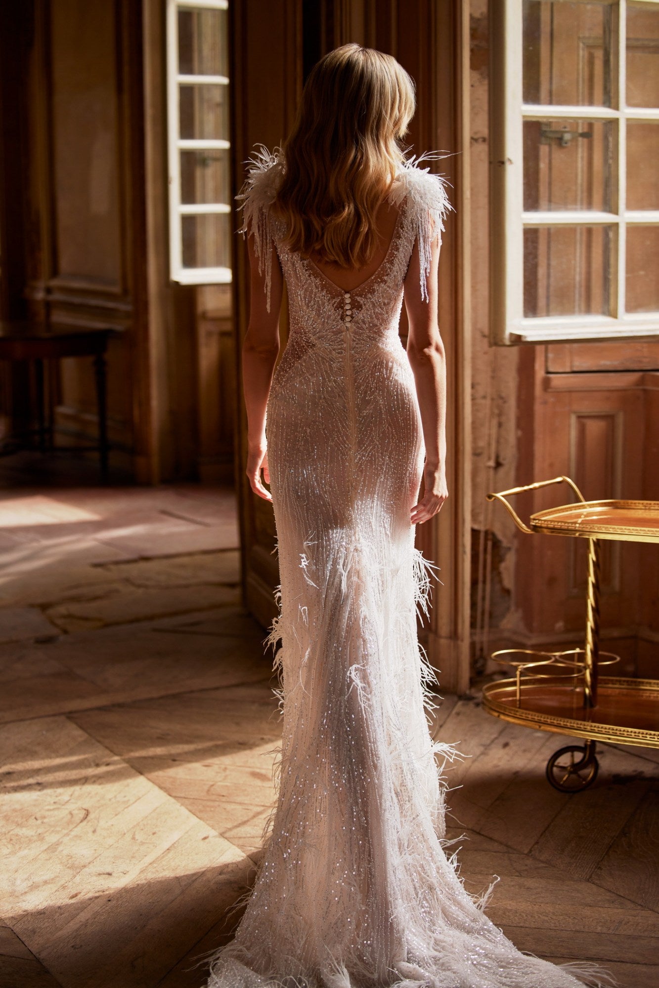 Get ready to turn heads in this one-of-a-kind Dress Feline! Featuring a sheer nude fabric with a delicate train, a V-neck corset, and intricate embroidered lace adorned with beads and glitter. The unique touches of feathers, crystals, and hand-made flowers on the shoulders will make you feel like a glamorous feline.