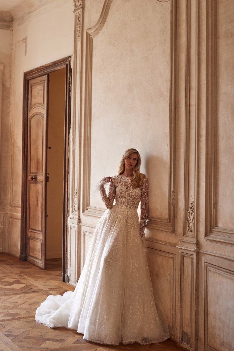 Experience elegance and style in Dress Evelyn. Featuring a detachable bodice, hidden zipper, and intricate lace and beadwork, this nude dress is perfect for any special occasion. The lace bolero with long sleeves and ruffled cuffs adds a touch of romance. Perfectly detailed with hand embroidered accents and 3D flowers.