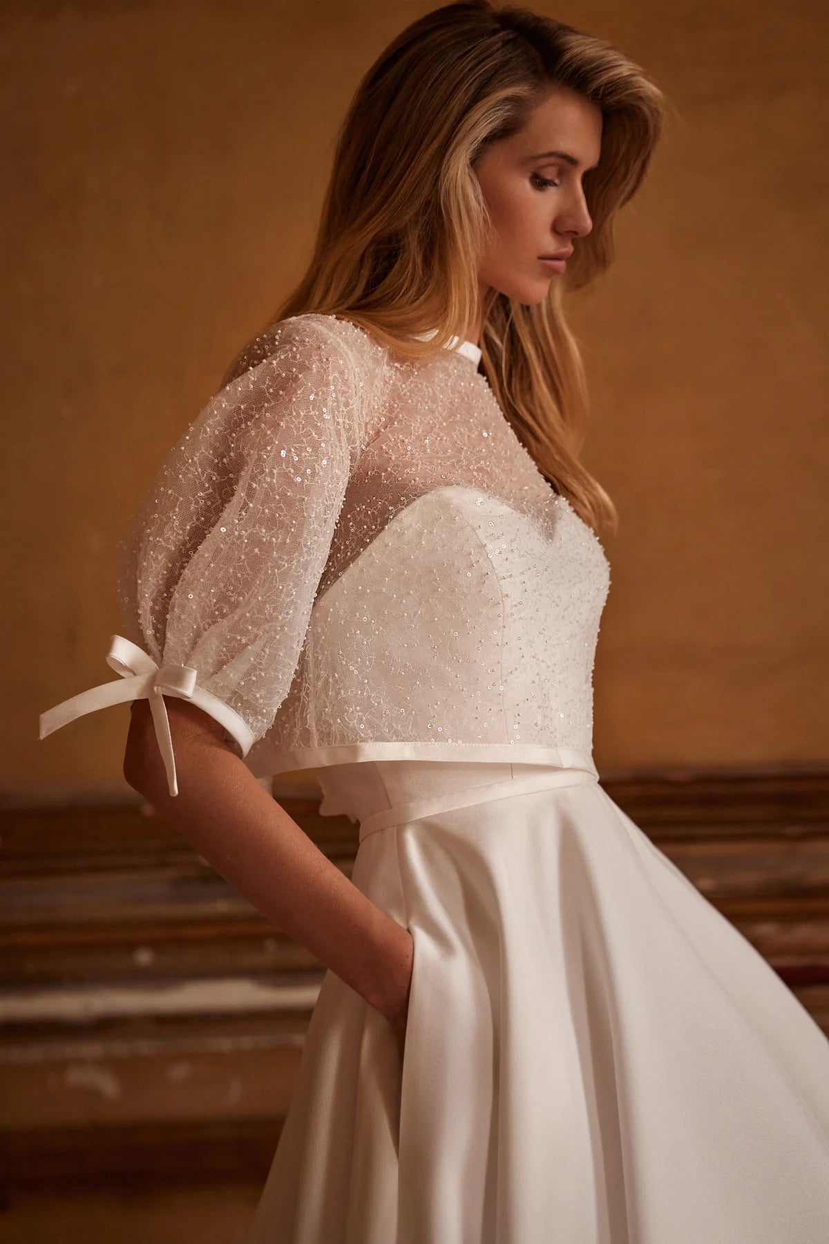 Elegant and timeless, the Ivory Mikado Robe Trudy is perfect for your special day. The structured corset, complete with a sweetheart neckline and internal lacing, ensures a flattering and secure fit. The flared skirt with pockets adds a modern touch to this classic wedding dress.