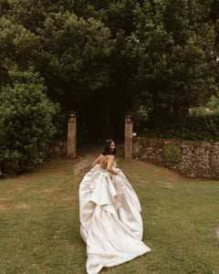 Get ready to walk down the aisle in style with our Romina Gown! This vintage-inspired wedding dress features a stunning backless design, elegant puff sleeves, and a flattering A-line silhouette. Made with soft, stain-resistant fabric, it's the perfect choice for your big day.
