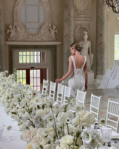 Get ready to dazzle on your special day with the Versy Gown. The fitted silhouette is enhanced by a relief corset made of transparent mesh and lace, adorned with asymmetrical pearl threads. The whimsical silhouette skirt features scattered pearl threads and removable stars for a unique, ethereal touch. Say "I do" in style with the Versy Gown.