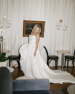 Indulge in the luxurious Arisa Gown: an exquisite dress featuring a minimalist design and made with high-quality fabrics like satin and mesh. The corset's off-shoulder straps create a stunning silhouette, while the versatile fitted and voluminous skirts allow for two elegant and sophisticated styles. In elegant ivory color.