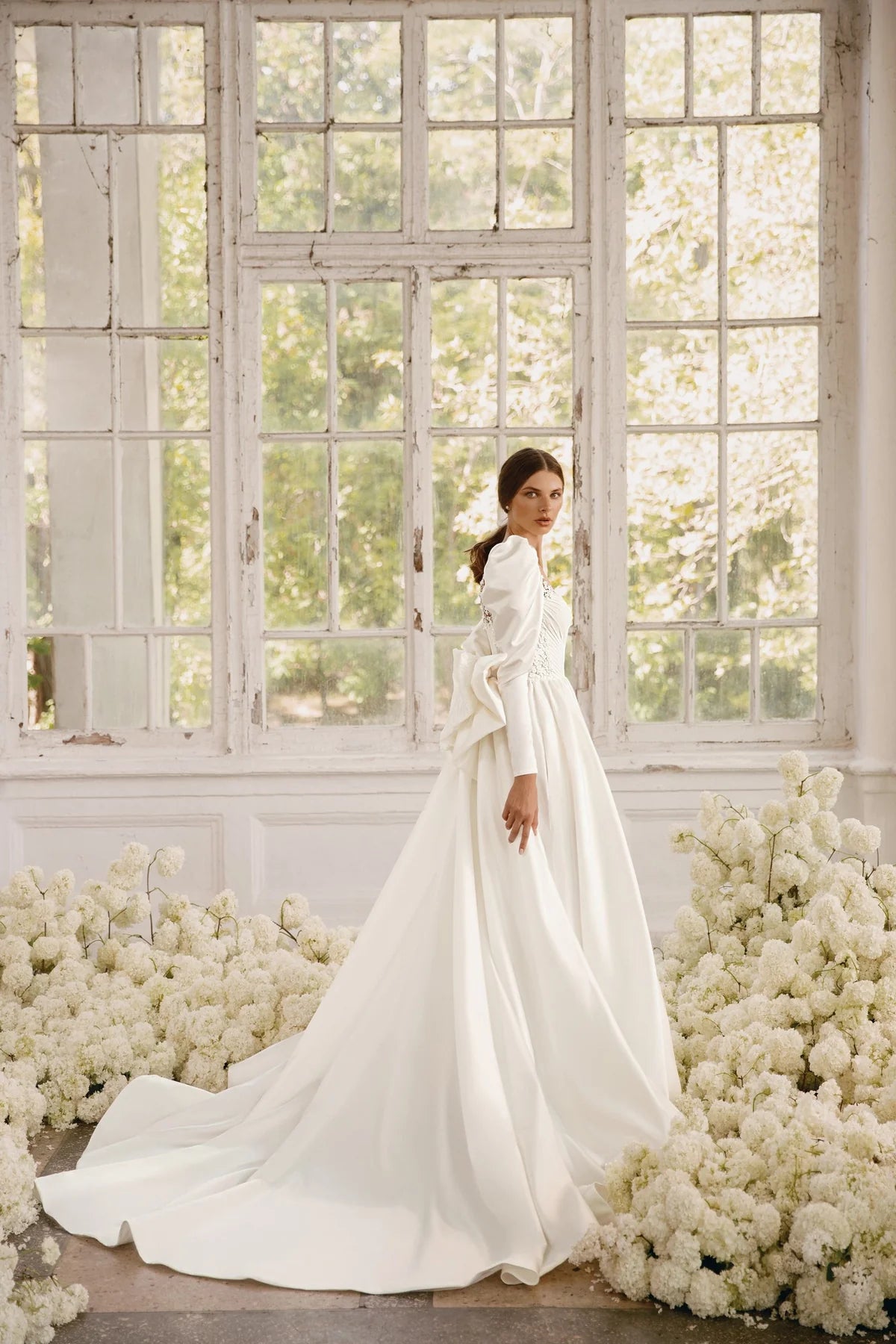 The Rosalee Gown is a breathtaking A-line wedding dress made of luxurious silk satin. The stunning corset features a unique draped design and voluminous puffed sleeves, while delicate hand-embroidered lace adorns the neckline and waistline. With hidden pockets and a removable sash, this dress effortlessly combines elegance and practicality.