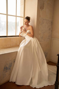 Elevate your special day with the Blue Gown. Made from luxurious Silk Mikado, it features a strapless sweetheart corset and basque waist for a flattering fit. The unique bow-shaped off-shoulder sleeves, coordinating gloves, and matching veil add a touch of elegance and sophistication. Create unforgettable memories in this stunning princess gown.
