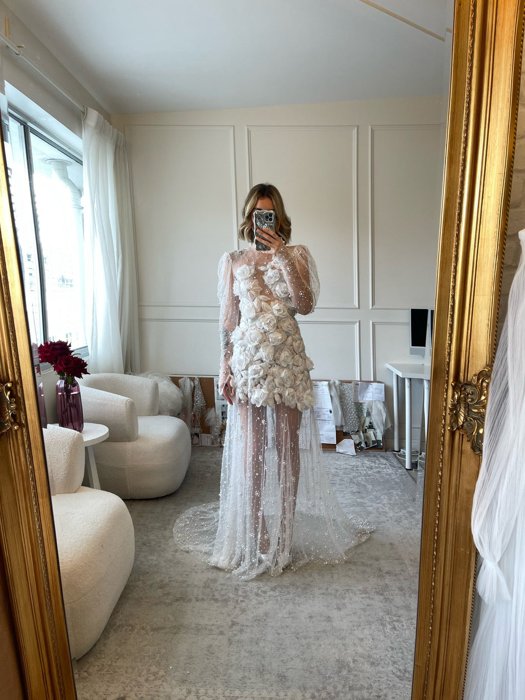 The Scarlett Dress is a dream come true for the romantic bride. Crafted from soft tulle, the bodice is adorned with delicate pearl beading and stunning 3D floral appliques, while the long sleeves and sheer godet skirt add a touch of whimsy and movement. Make a statement on your special day with this magical design.
