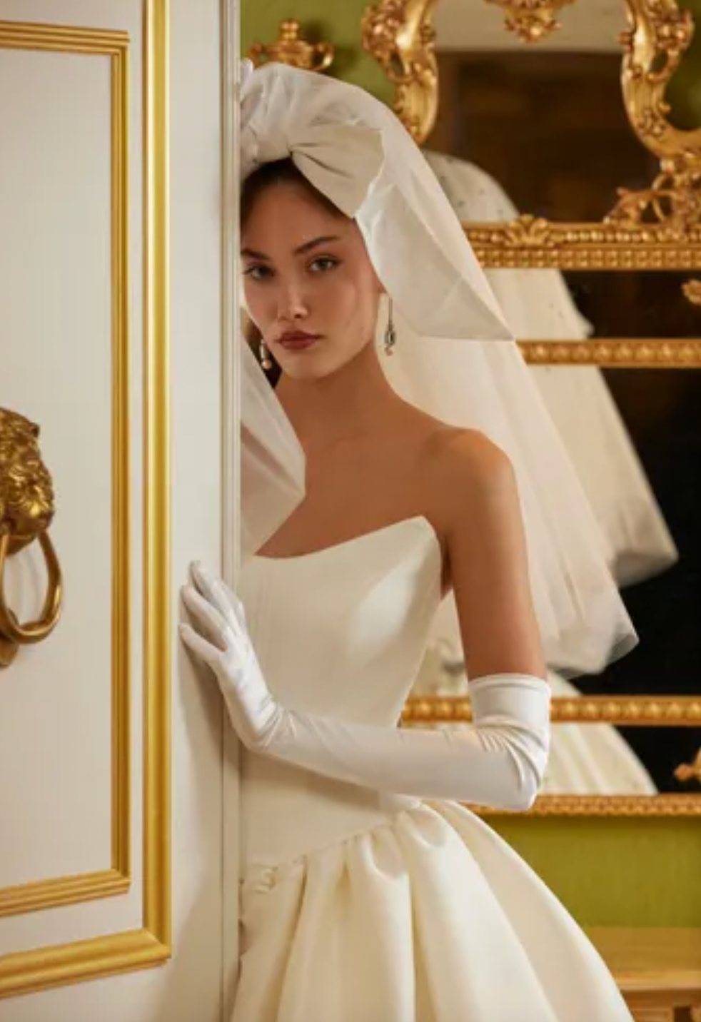 Luxurious and elegant, the Demia Gown is crafted from Italian Stretch Mikado fabric and features a cat eye neckline and basque waist for a flattering silhouette. The pleated and gathered ballgown is adorned with signature bow accents on the back bodice, making it a perfect pick for a special occasion.