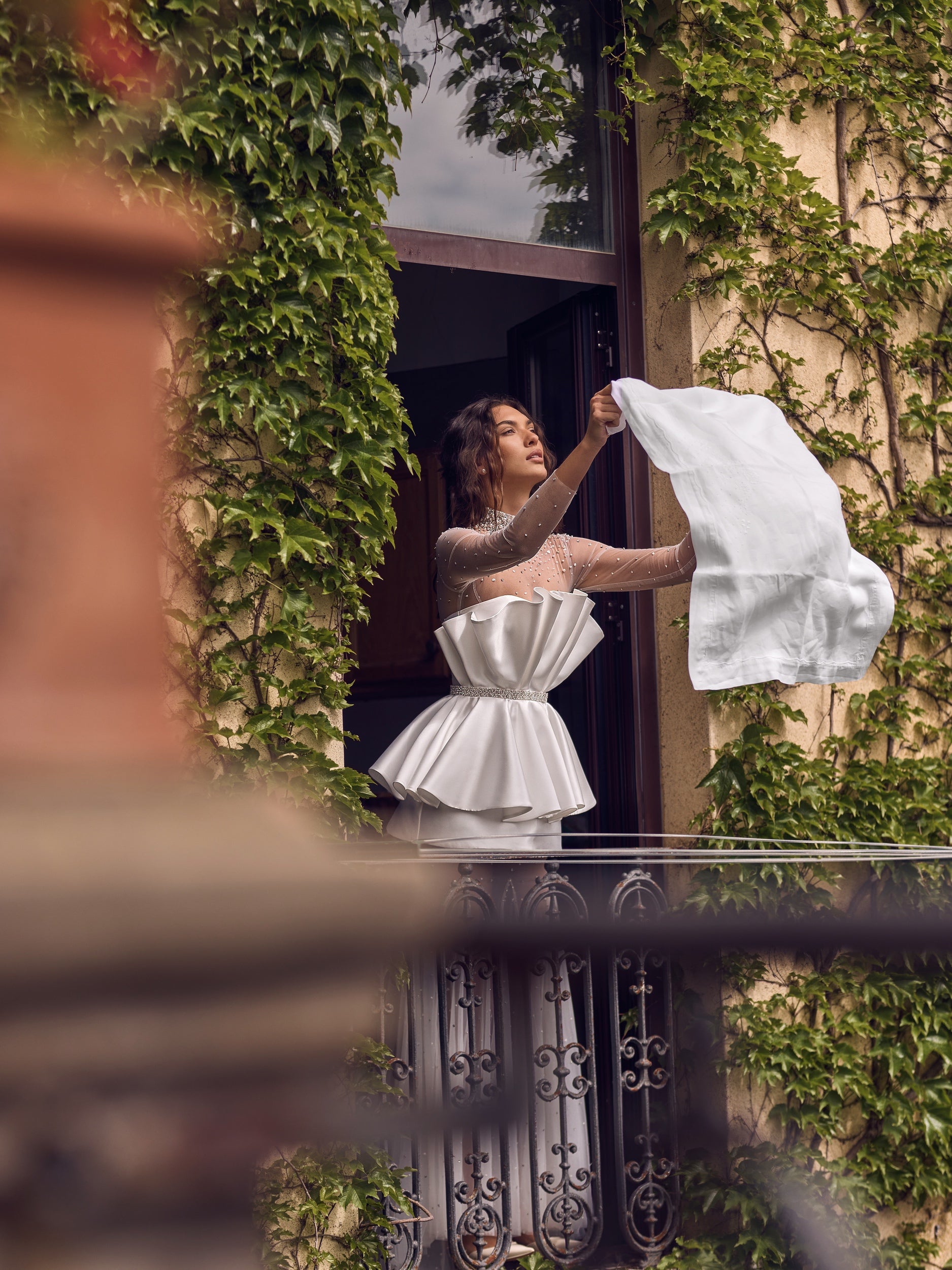 The Cassiopeia Gown captivates with its extraordinary seashell-inspired silhouette and radiant shimmer. Crafted from glossy mikado and crystal-embellished tulle, it features a neckline richly detailed with crystals and pearls for a sophisticated focal point. The bodice secures with hooks and a hidden snap at the waist, complemented by a matching embellished belt that defines the figure. 