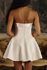 This elegant Strapless Opera Mini Dress in Pearl features a fold-over collar and a silicone gripper elastic that ensures a secure fit along the inner bodice. Designed with godets at the high hip and discreet built-in pockets, it offers both structure and functionality. The dress closes with an invisible zipper and hook-and-eye at the center back, enhanced by boning along the side seams and back for added support. 