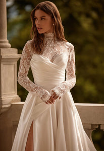 Elegant and luxurious, the Petal Gown is a beautiful option for the delicate and determined bride. The A-line silhouette is made of Mikado fabric, with a corset featuring a unique heart cutout and nude-colored mesh insert. The back of the corset is adorned with horizontal pleats and fastened with expander hooks. The full skirt, also in Mikado fabric, has a playful slit and diagonal pleating on the front panel.