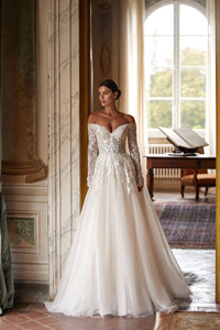 Introducing the Regina Gown, a light skin A-line dress that will make any bride the star of the wedding. The semi-sheer corset with a deep heart cutout and embroidered lace patterns adds a seductive touch, while the fluffy skirt and luxurious train create a stunning silhouette. Available in ivory.