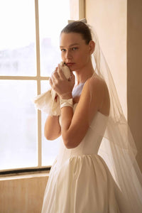 Elevate your special day with the Blue Gown. Made from luxurious Silk Mikado, it features a strapless sweetheart corset and basque waist for a flattering fit. The unique bow-shaped off-shoulder sleeves, coordinating gloves, and matching veil add a touch of elegance and sophistication. Create unforgettable memories in this stunning princess gown.
