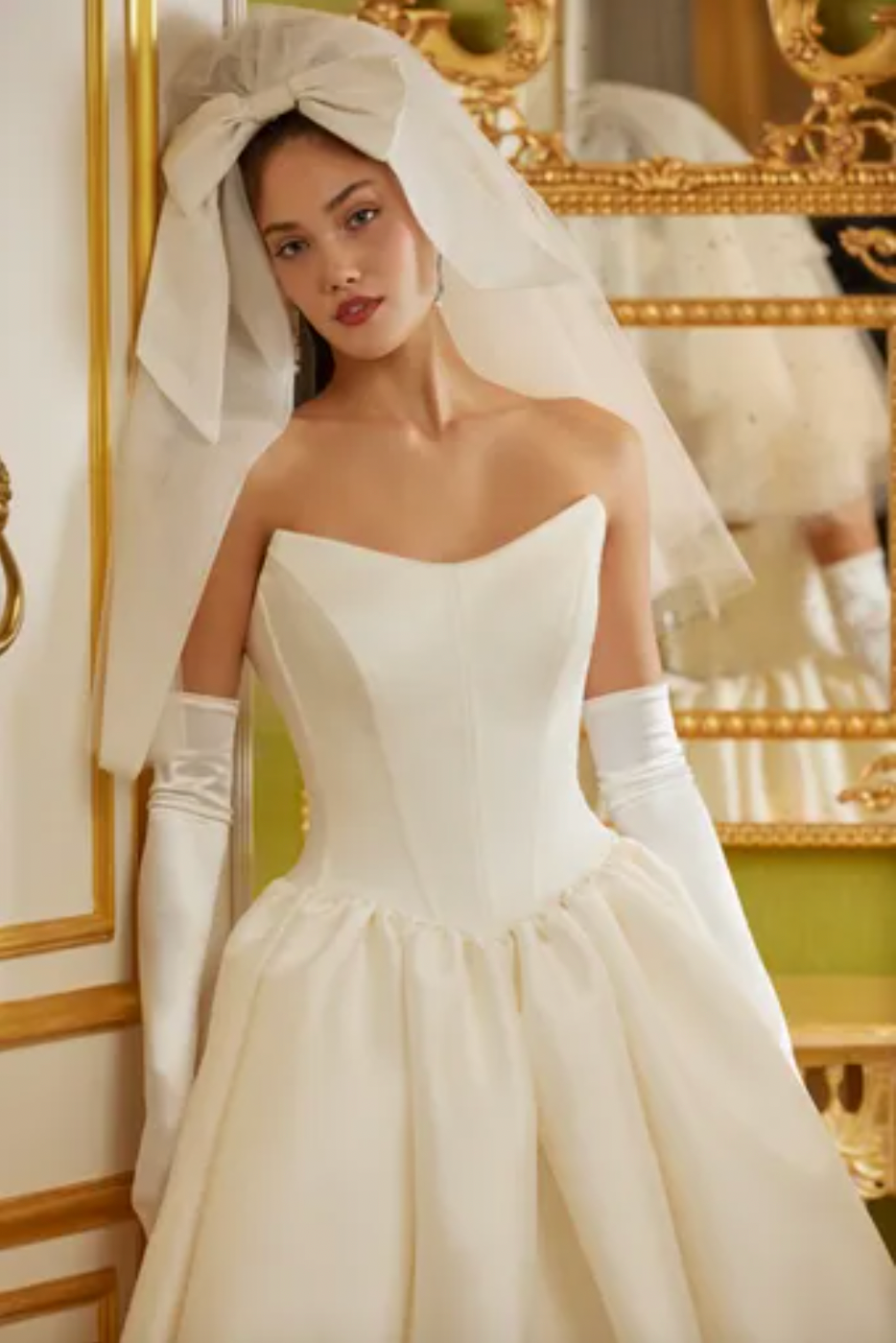 Luxurious and elegant, the Demia Gown is crafted from Italian Stretch Mikado fabric and features a cat eye neckline and basque waist for a flattering silhouette. The pleated and gathered ballgown is adorned with signature bow accents on the back bodice, making it a perfect pick for a special occasion.