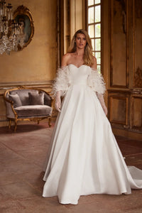 Elegant and timeless, the Ivory Mikado Robe Trudy is perfect for your special day. The structured corset, complete with a sweetheart neckline and internal lacing, ensures a flattering and secure fit. The flared skirt with pockets adds a modern touch to this classic wedding dress.