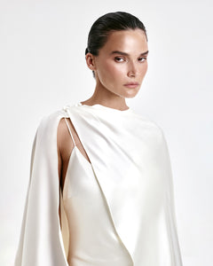 A laconic cape with a smooth texture — a luxurious attribute of the image that emphasizes the elegance and inner strength of its owner. The soft overflow of the fabric, the exquisite silhouette and train make the product expressive and self-sufficient. The composition was chosen consciously: the material does not wrinkle, retains its shape and provides an impeccable appearance throughout the evening. Becomes the final chord in a special event without requiring additional details. 