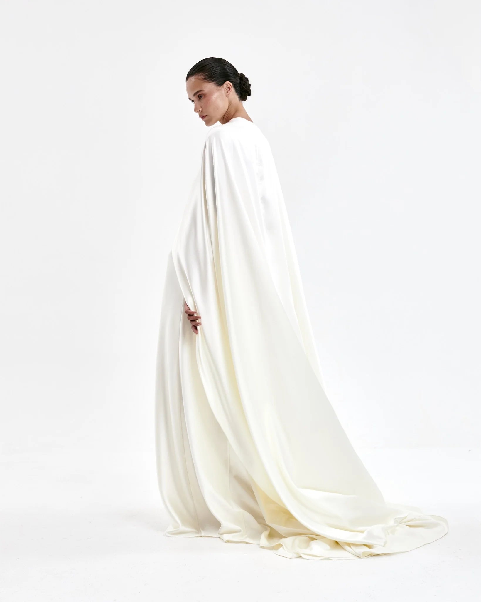 A laconic cape with a smooth texture — a luxurious attribute of the image that emphasizes the elegance and inner strength of its owner. The soft overflow of the fabric, the exquisite silhouette and train make the product expressive and self-sufficient. The composition was chosen consciously: the material does not wrinkle, retains its shape and provides an impeccable appearance throughout the evening. Becomes the final chord in a special event without requiring additional details. 