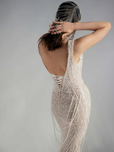 Get ready to dazzle on your special day with the Versy Gown. The fitted silhouette is enhanced by a relief corset made of transparent mesh and lace, adorned with asymmetrical pearl threads. The whimsical silhouette skirt features scattered pearl threads and removable stars for a unique, ethereal touch. Say "I do" in style with the Versy Gown.