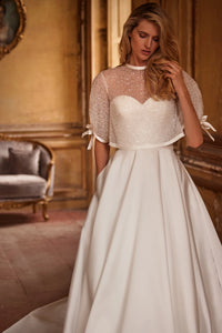 Elegant and timeless, the Ivory Mikado Robe Trudy is perfect for your special day. The structured corset, complete with a sweetheart neckline and internal lacing, ensures a flattering and secure fit. The flared skirt with pockets adds a modern touch to this classic wedding dress.