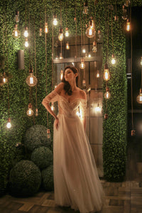 Elevate your special day with our Robe Mae. The elegant column silhouette features stunning beaded lace for a touch of glamour, while the off-shoulder sheer sleeves and deep v-neckline add a hint of romance. Complete the look with the delicate tulle skirt, for a dreamy and unforgettable bridal ensemble.