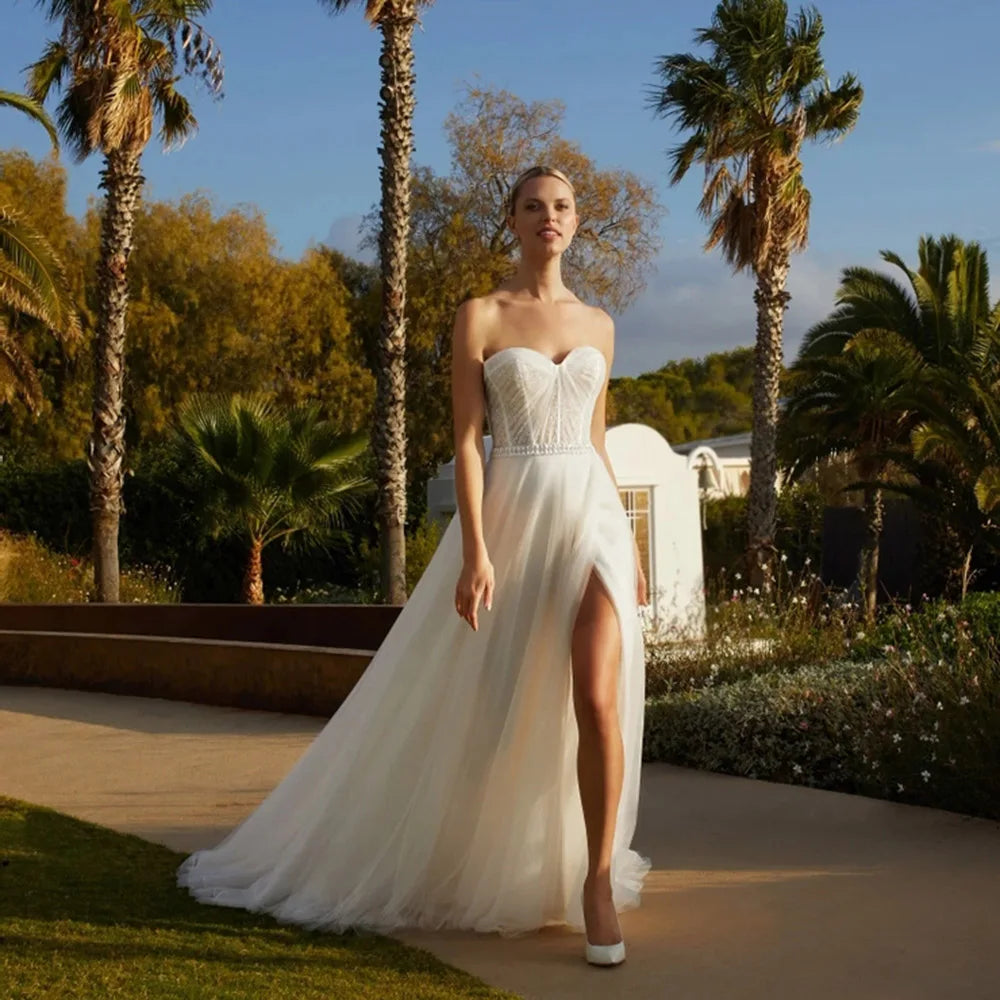 Robe Courtney is a stunning wedding dress that exudes sophistication and luxury. Crafted with simple yet elegant details such as a sleeveless silhouette, shiny A-line skirt, and beautiful side split, this dress highlights your figure without compromising comfort. Complete with a sweetheart neckline, pleats, lace belt, and backless design, you'll look like royalty on your special day.