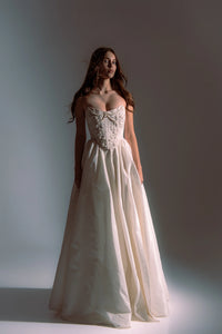Indulge in elegance and comfort with the Katherine Gown. Adorned with exquisite beaded appliqués, the taffeta corset ensures a flawless fit, while the lined leg slit skirt adds a touch of refinement. Step out in style and radiate beauty with each stride.