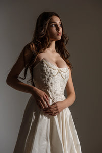 Indulge in elegance and comfort with the Katherine Gown. Adorned with exquisite beaded appliqués, the taffeta corset ensures a flawless fit, while the lined leg slit skirt adds a touch of refinement. Step out in style and radiate beauty with each stride.