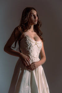 Indulge in elegance and comfort with the Katherine Gown. Adorned with exquisite beaded appliqués, the taffeta corset ensures a flawless fit, while the lined leg slit skirt adds a touch of refinement. Step out in style and radiate beauty with each stride.