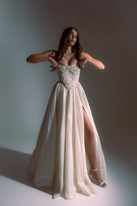 Indulge in elegance and comfort with the Katherine Gown. Adorned with exquisite beaded appliqués, the taffeta corset ensures a flawless fit, while the lined leg slit skirt adds a touch of refinement. Step out in style and radiate beauty with each stride.
