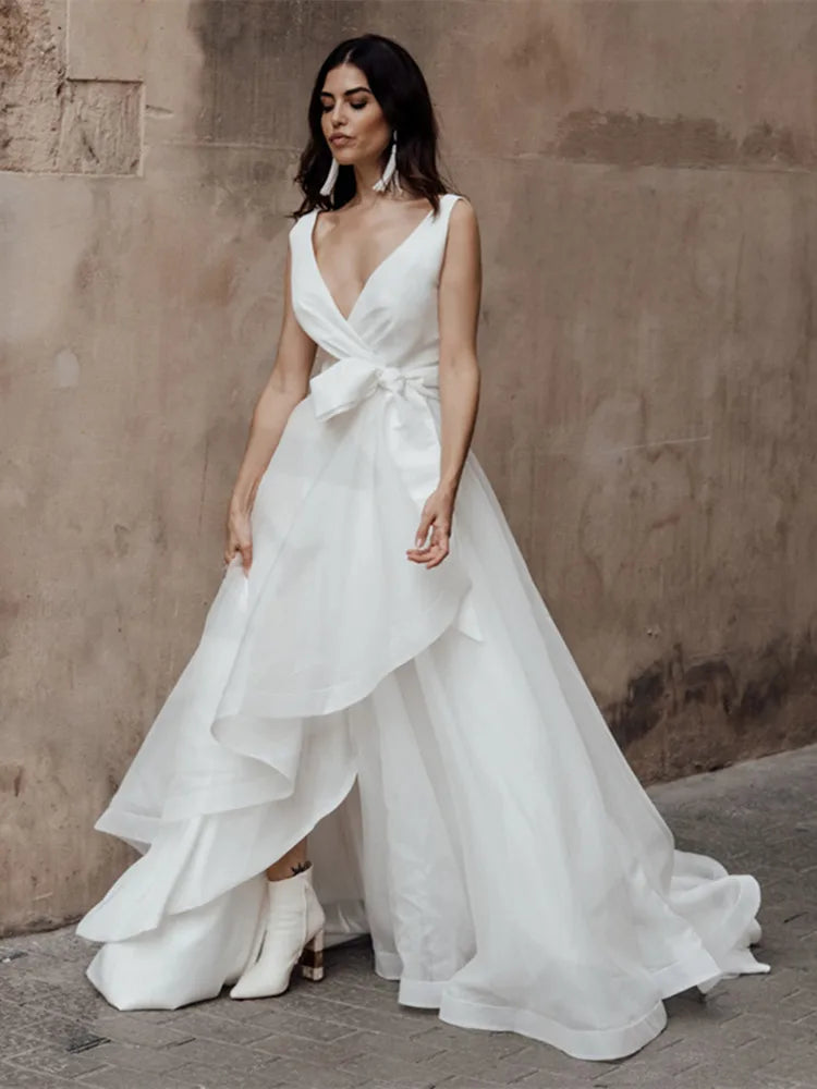 Get ready to turn heads in the Dress Safira! This simple yet stunning wedding dress features a V-neck and sleeveless design, perfect for showing off your curves. The added bow detail and backless style add an extra touch of sexiness, while the tiered skirt adds dimension and movement. Say "I do" in style.