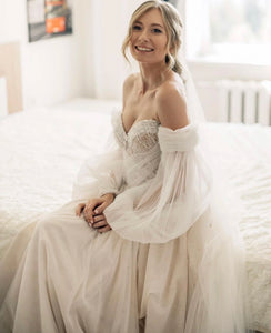 Indulge in luxury with our Robe Johanna, a boho wedding dress with A-line silhouette and sweetheart neckline. The lantern sleeves and off-shoulder design add a touch of elegance, while the criss-cross back and intricate beadwork make for a truly unique piece. Be the center of attention in this floor-length gown, perfect for any bride looking for something new and stunning.