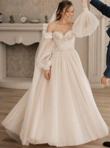 Indulge in luxury with our Robe Johanna, a boho wedding dress with A-line silhouette and sweetheart neckline. The lantern sleeves and off-shoulder design add a touch of elegance, while the criss-cross back and intricate beadwork make for a truly unique piece. Be the center of attention in this floor-length gown, perfect for any bride looking for something new and stunning.