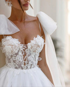 Introducing the Robe Allura - a stunning luxury lace wedding dress with delicate shoulder bows and elegant lace appliques. Designed in a flattering A-line silhouette, this dress is perfect for princess brides with a bohemian touch. Look and feel like a true wedding day princess in this breathtaking gown.