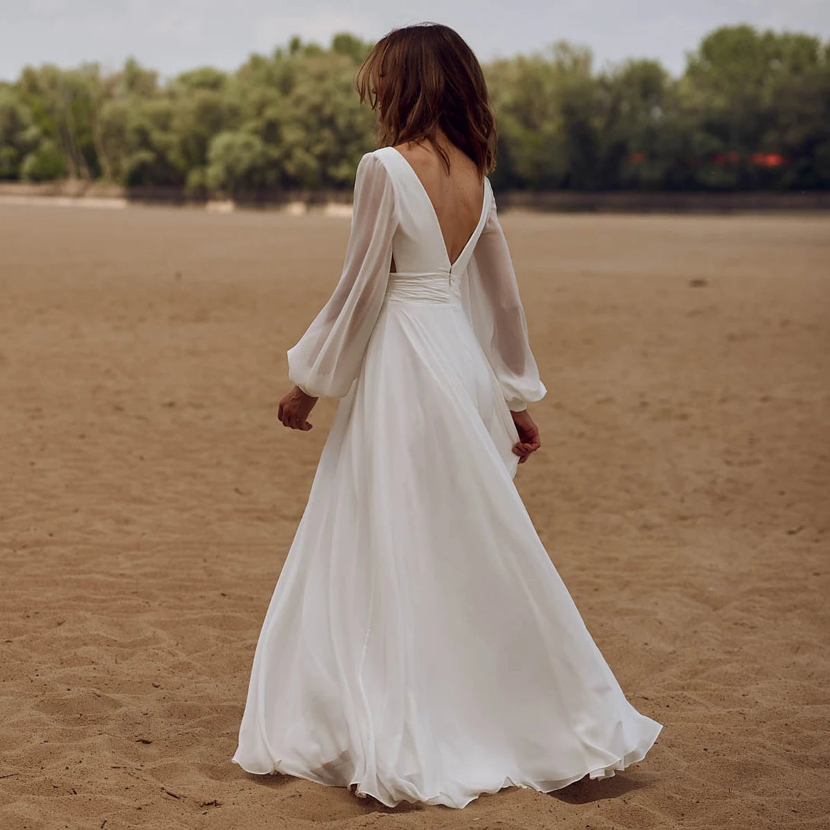 Look effortlessly elegant on your special day with our Dress Sidnea. This maxi floor length chiffon wedding dress features long bishop sleeves, a v-neckline, and a backless design for a touch of sophistication. The self-tie sash adds a feminine silhouette while the high cut showcases your figure. Say "I do" in style with this stunning dress.