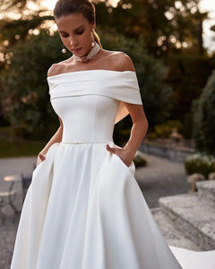 Indulge in luxury on your special day with the Robe Lotta. Featuring an elegant white A-line design and an off-the-shoulder neckline, this wedding dress is made of smooth satin for a sophisticated look and feel. Make a statement that exudes grace and refinement with this exclusive piece.