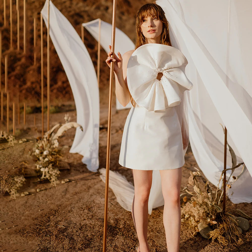 Perfect for your special day, this gorgeous Robe Brittany features beautiful handmade flowers, petite pearls and spaghetti straps that'll make sure you feel like royalty. With a classic strapless mini satin look and a simple backless style, you'll look stunning no matter the occasion!