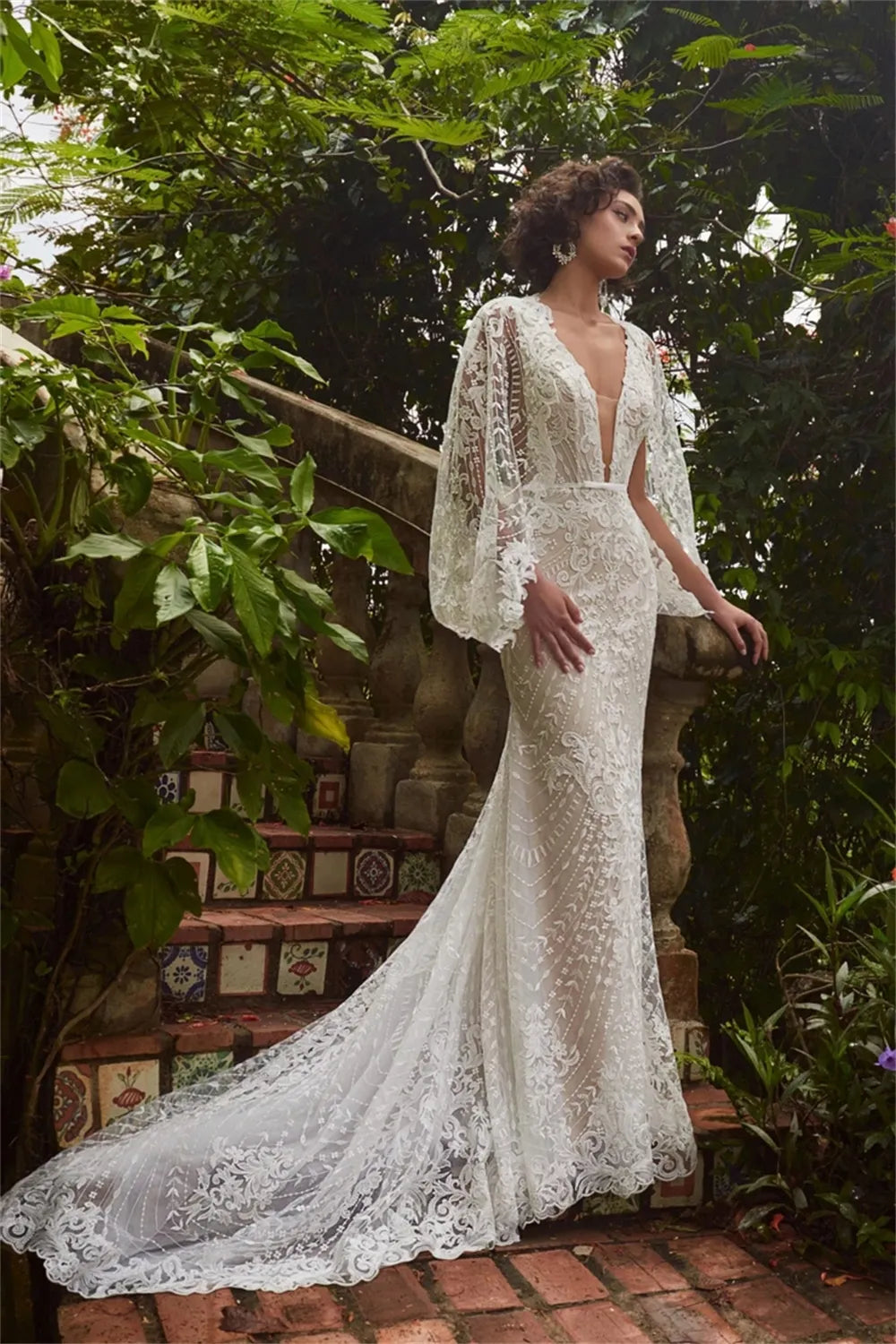Elevate your special day in the Robe Jacqueline. This exquisite mermaid-style dress is crafted with V-neck and brush floor-length silhouette. Featuring an open back and handmade flower lace accents, this wedding dress is sure to make an unforgettable impression.