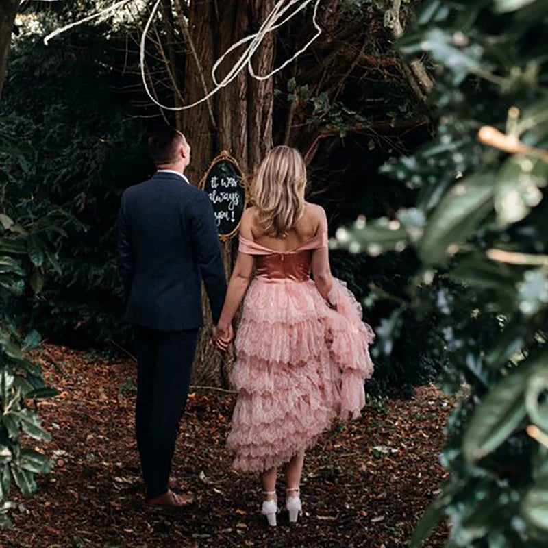 Elevate your wedding day in the exquisite off shoulder Robe Melissa. Crafted with delicate tiered lace in a dreamy mauve pink hue, this A-line custom-made gown is perfect for the plus-size bride. With a breathtaking long train and tutu details, this dress is a must-have for your elopement photoshoot.