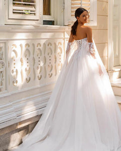 This dress captures the essence of bohemian style with its off-the-shoulder design and intricate lace appliques. Perfect for a vintage-inspired wedding, it features a timeless ball gown silhouette and shimmering sequin accents. Feel confident and radiant on your special day with Dress Camille!