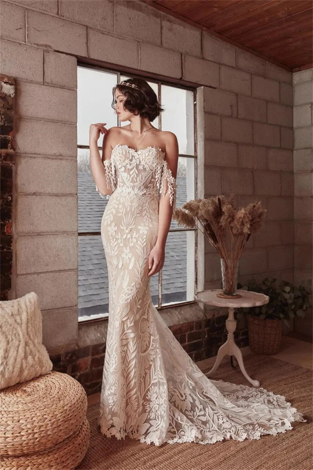 This Robe Cosette wedding dress is the perfect mix of sweet and sexy. The sheath silhouette and delicate lace fabric are complemented by an off-the-shoulder neckline and sweep train. Highly flattering and comfortable, this bridal gown is perfect for a church or civil wedding.